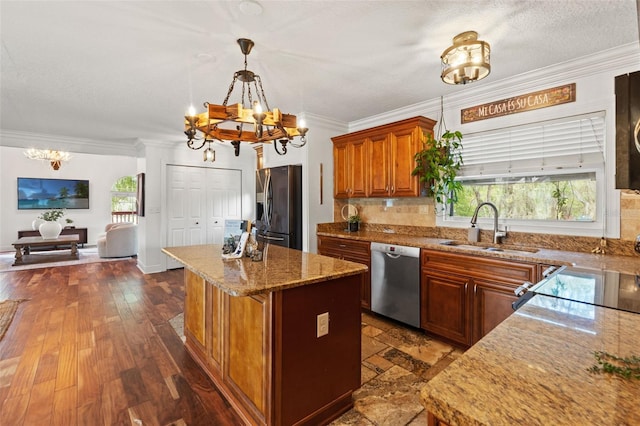 kitchen featuring a kitchen island, crown molding, a notable chandelier, stainless steel appliances, and a sink