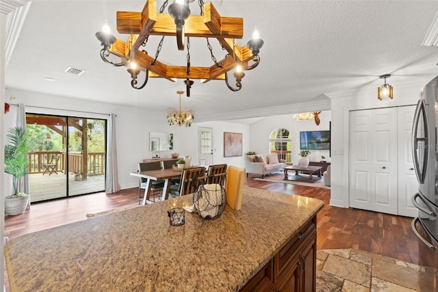 kitchen with a wealth of natural light, visible vents, an inviting chandelier, and freestanding refrigerator