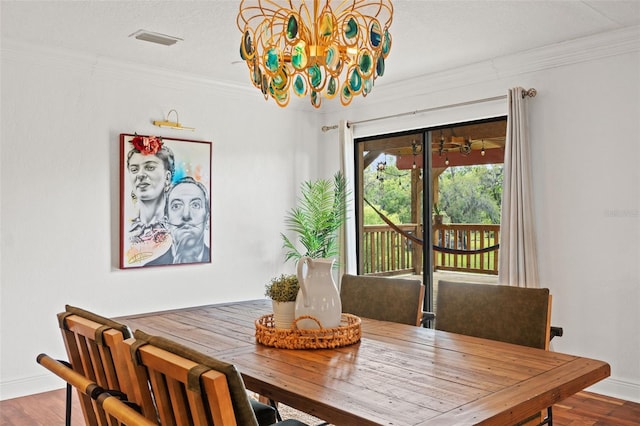 dining room with a notable chandelier, wood finished floors, visible vents, and ornamental molding