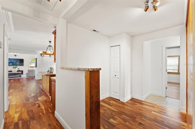 corridor featuring a wealth of natural light, visible vents, an inviting chandelier, and light wood finished floors