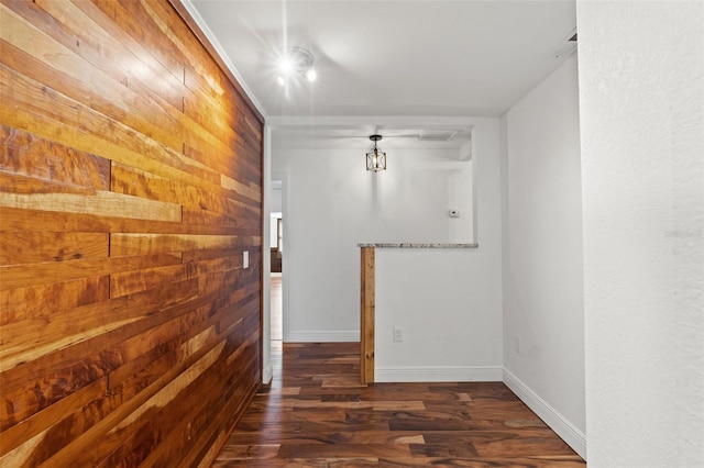 unfurnished room with baseboards, wood finished floors, and wood walls