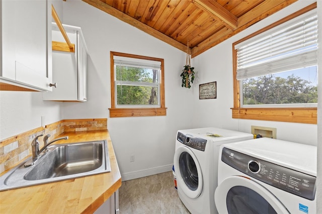 laundry area featuring baseboards, cabinet space, a sink, wooden ceiling, and washer and clothes dryer