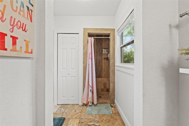 corridor with stone finish floor and baseboards