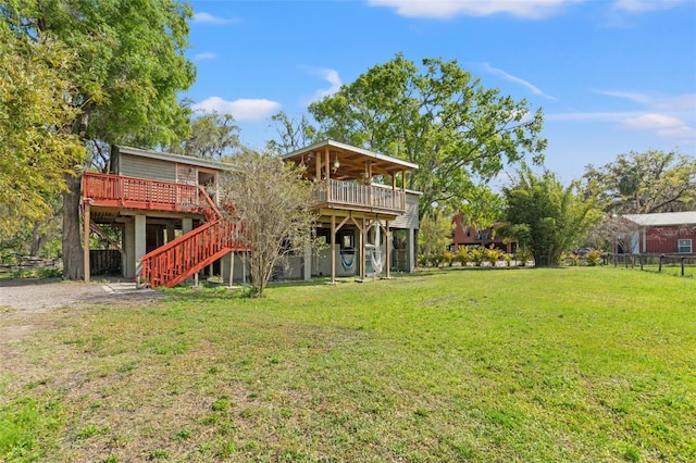 back of house featuring a lawn, a deck, and stairs