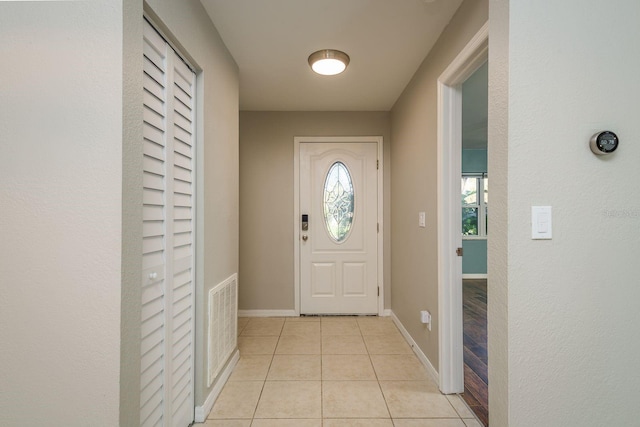 doorway to outside with light tile patterned floors, visible vents, a healthy amount of sunlight, and baseboards