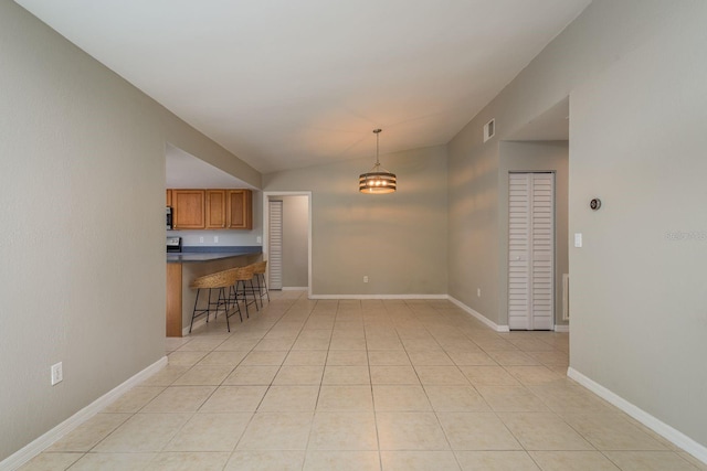 interior space with light tile patterned floors, visible vents, baseboards, and lofted ceiling