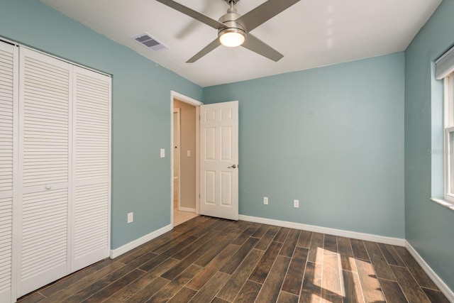 unfurnished bedroom featuring visible vents, baseboards, a closet, dark wood-style floors, and a ceiling fan