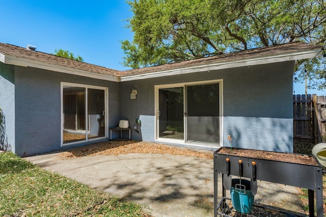 rear view of property with stucco siding and fence