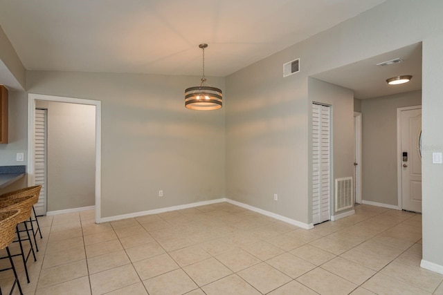 unfurnished dining area with light tile patterned floors, baseboards, and visible vents