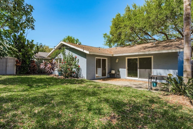 back of house with a yard, stucco siding, and a patio