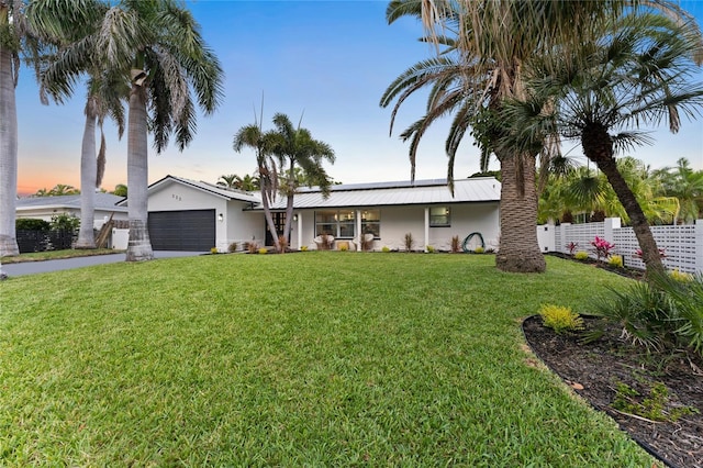 view of front of house featuring fence, driveway, stucco siding, a front lawn, and a garage