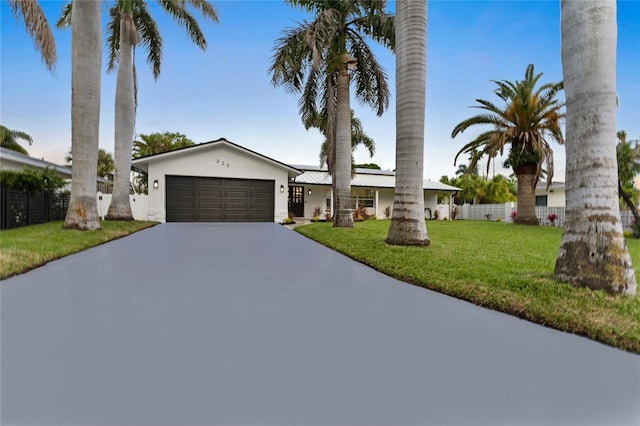 view of front of house featuring a front lawn, fence, concrete driveway, metal roof, and a garage