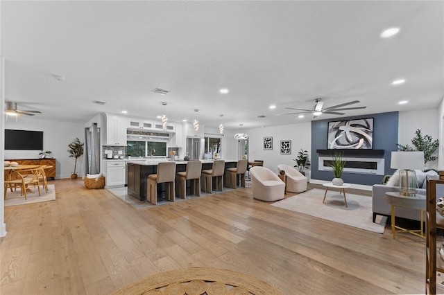 living area featuring recessed lighting, visible vents, ceiling fan, and light wood finished floors