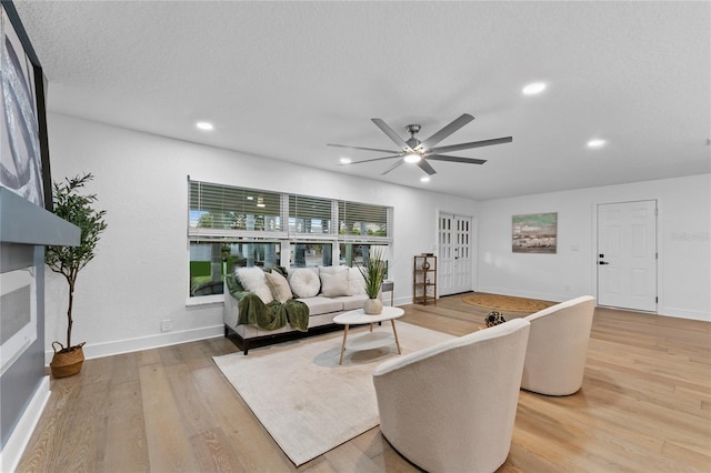 living room featuring baseboards, light wood-type flooring, recessed lighting, a textured ceiling, and a ceiling fan