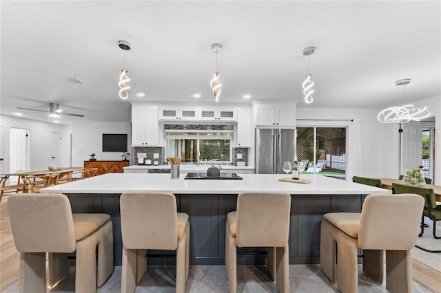 kitchen featuring a breakfast bar, a large island, light countertops, high end refrigerator, and white cabinetry