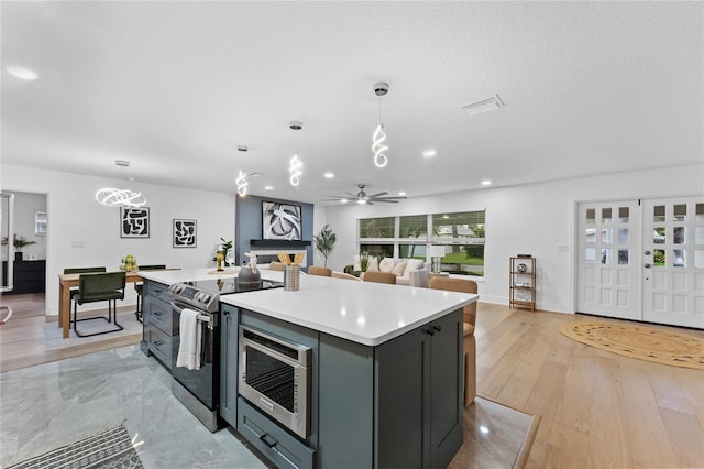 kitchen featuring decorative light fixtures, stainless steel appliances, a center island, and light countertops