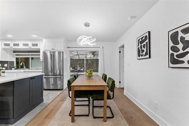 dining room with a chandelier, light wood-style flooring, and baseboards