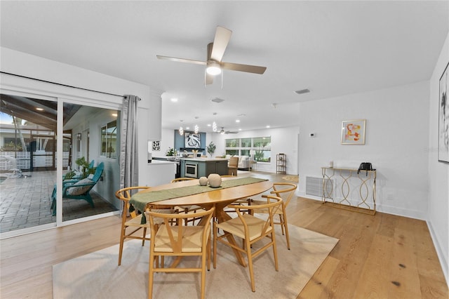 dining space with light wood-style flooring, baseboards, visible vents, and ceiling fan