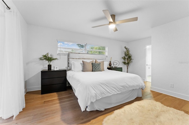 bedroom featuring ceiling fan, connected bathroom, baseboards, and wood finished floors