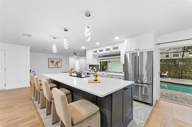 kitchen with light wood finished floors, high end refrigerator, white cabinetry, and visible vents