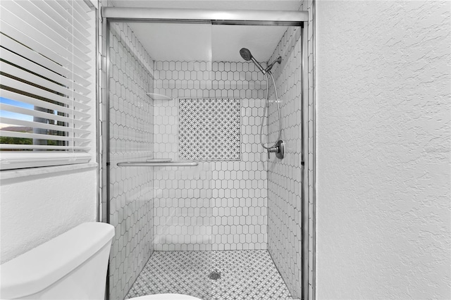 bathroom with a shower stall, toilet, and a textured wall