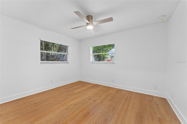 spare room featuring baseboards, ceiling fan, and light wood finished floors