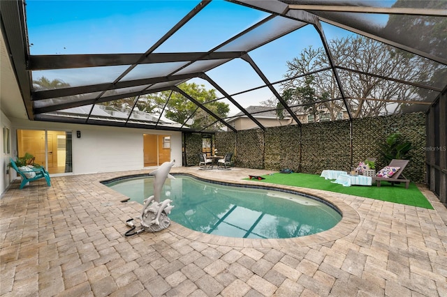 outdoor pool featuring glass enclosure and a patio area