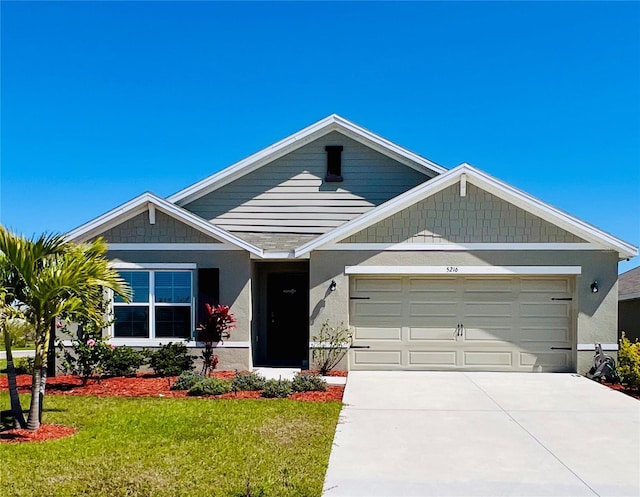 view of front of house featuring a front yard, an attached garage, driveway, and stucco siding