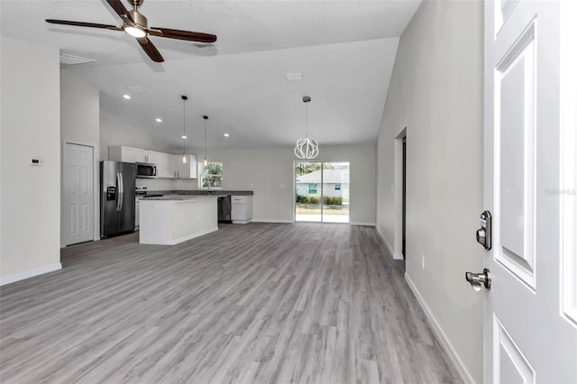 interior space with ceiling fan with notable chandelier, light wood-type flooring, and baseboards