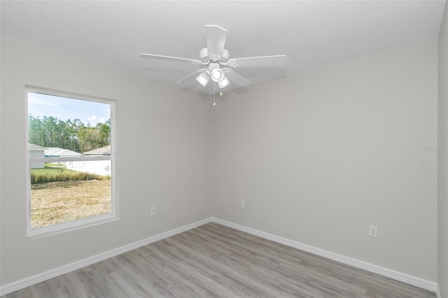 empty room featuring light wood finished floors, a ceiling fan, and baseboards