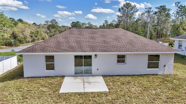 rear view of property with stucco siding, a patio, fence, a yard, and roof with shingles