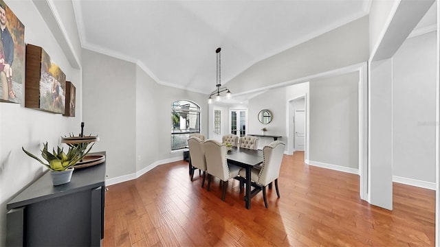 dining area with baseboards, lofted ceiling, light wood-style floors, and ornamental molding