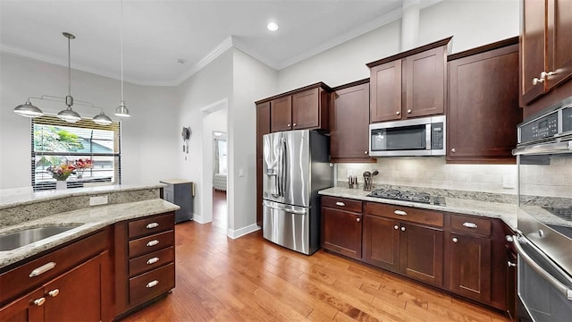 kitchen featuring light wood-style floors, stainless steel appliances, backsplash, and crown molding