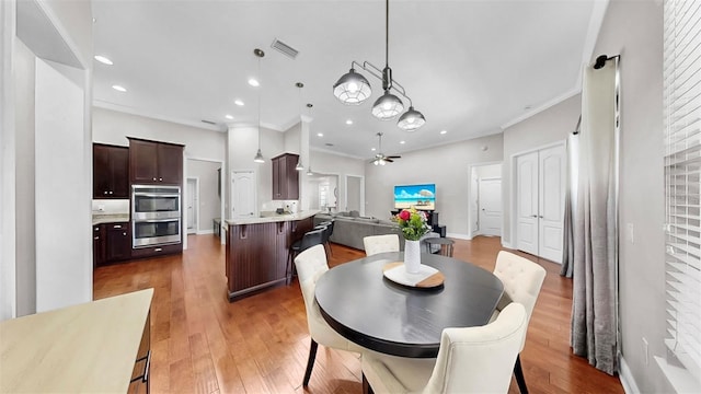 dining space with light wood finished floors, visible vents, recessed lighting, and crown molding