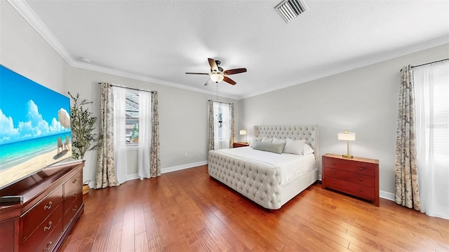 bedroom featuring visible vents, crown molding, ceiling fan, baseboards, and wood-type flooring