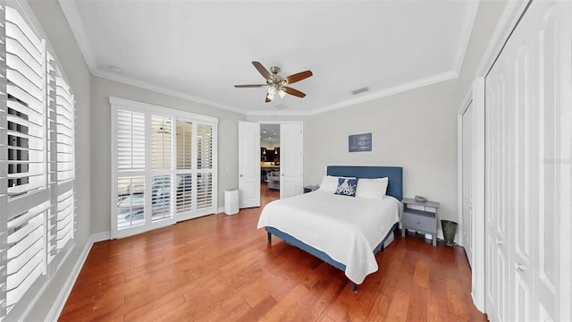 bedroom featuring visible vents, ornamental molding, ceiling fan, and wood finished floors