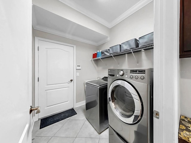 laundry area featuring baseboards, laundry area, light tile patterned flooring, ornamental molding, and washing machine and dryer