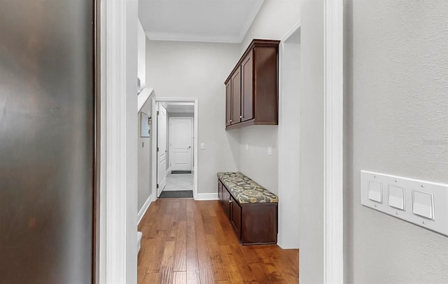 corridor featuring crown molding, baseboards, and wood-type flooring