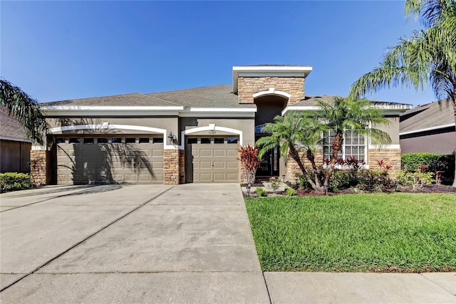 view of front of house featuring a front yard, stucco siding, a garage, stone siding, and driveway