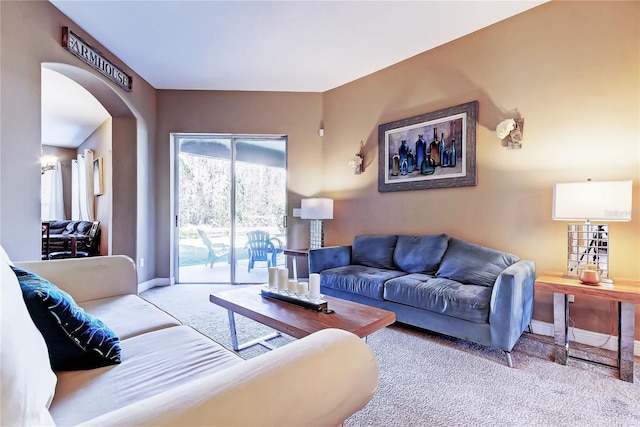 living area with carpet flooring, baseboards, and arched walkways