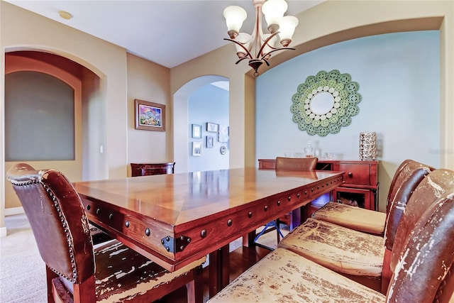 carpeted dining area featuring arched walkways and a notable chandelier