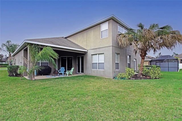 rear view of property featuring a patio, a yard, and stucco siding