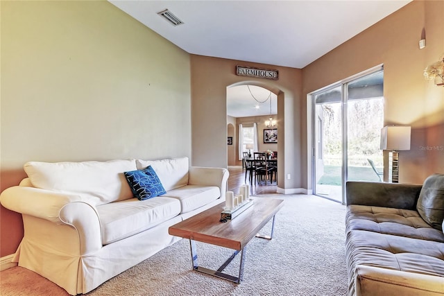 living area featuring visible vents, a notable chandelier, arched walkways, carpet flooring, and baseboards