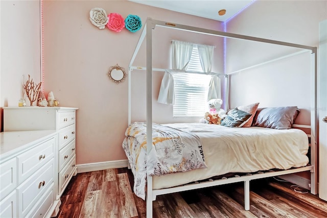 bedroom with baseboards and dark wood-type flooring