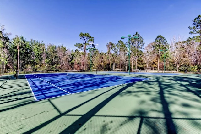 view of tennis court featuring community basketball court and fence