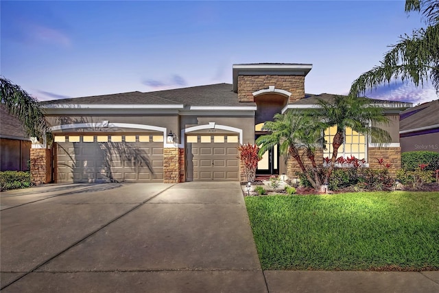 view of front facade with a front yard, stucco siding, a garage, stone siding, and driveway