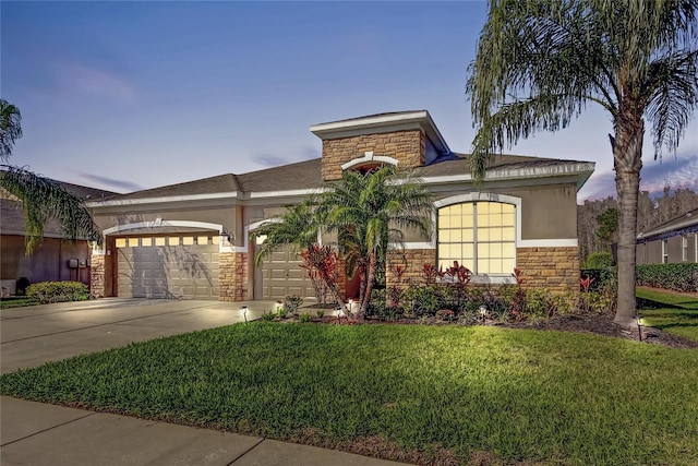 view of front of property featuring a front yard, driveway, an attached garage, stucco siding, and stone siding