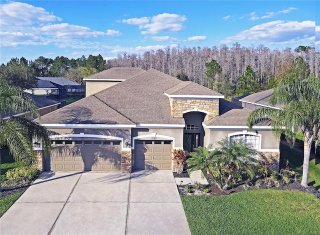 view of front facade with stucco siding, stone siding, driveway, and an attached garage