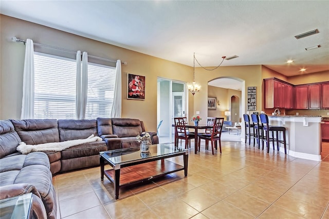 living area featuring arched walkways, light tile patterned floors, a notable chandelier, and visible vents