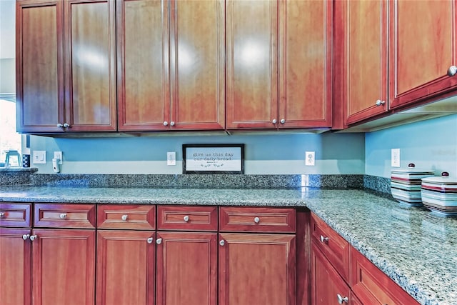 kitchen with dark stone counters and reddish brown cabinets